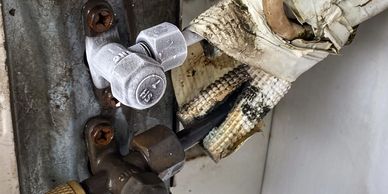 Close-up of corroded and wrapped pipes with valves and rusted screws.