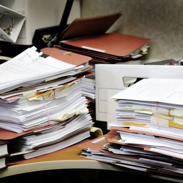 Messy dental office desk cluttered with piles of files