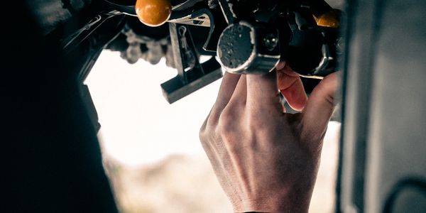 A hand operating a mechanical control with levers and knobs.