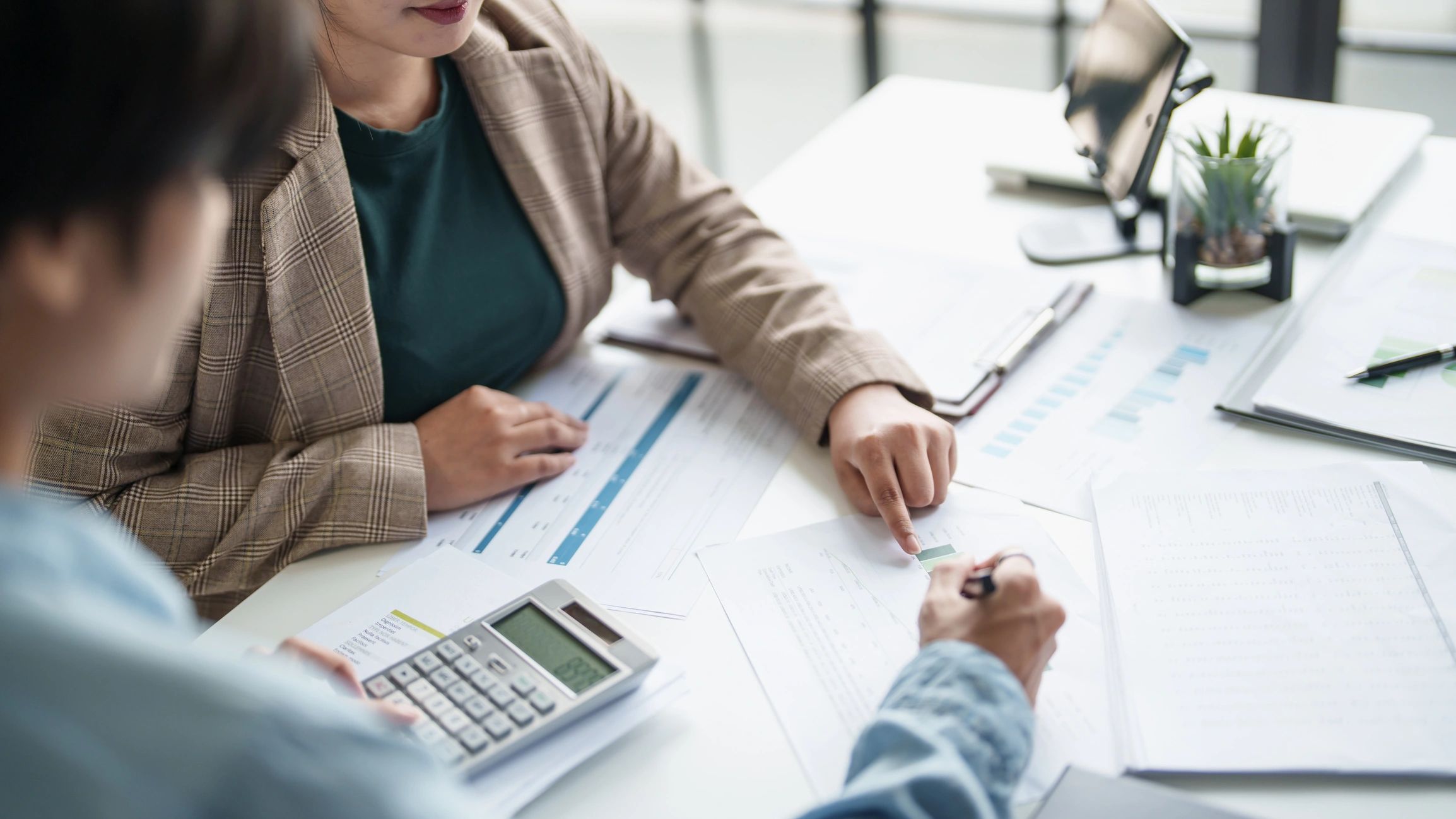 Two people discussing documents with a calculator on the table.