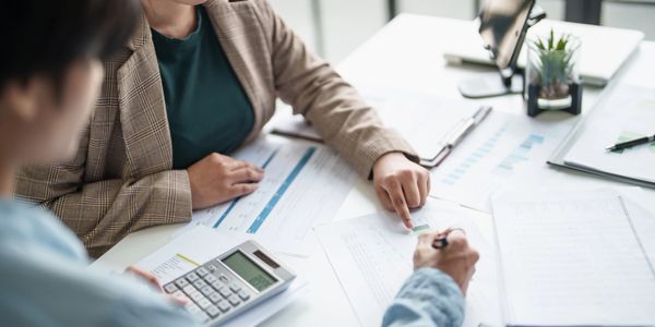 Two professionals reviewing documents and using a calculator at a desk.