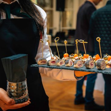 Server holding tray of appetizers with toothpicks.