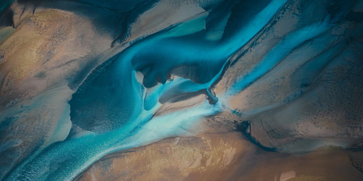 Aerial view of river channels with blue water and sandy banks.