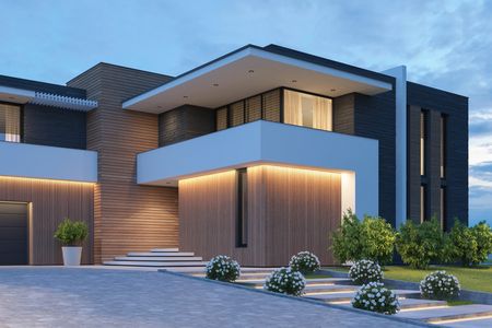 Modern house exterior with warm lighting and landscaped garden at dusk.