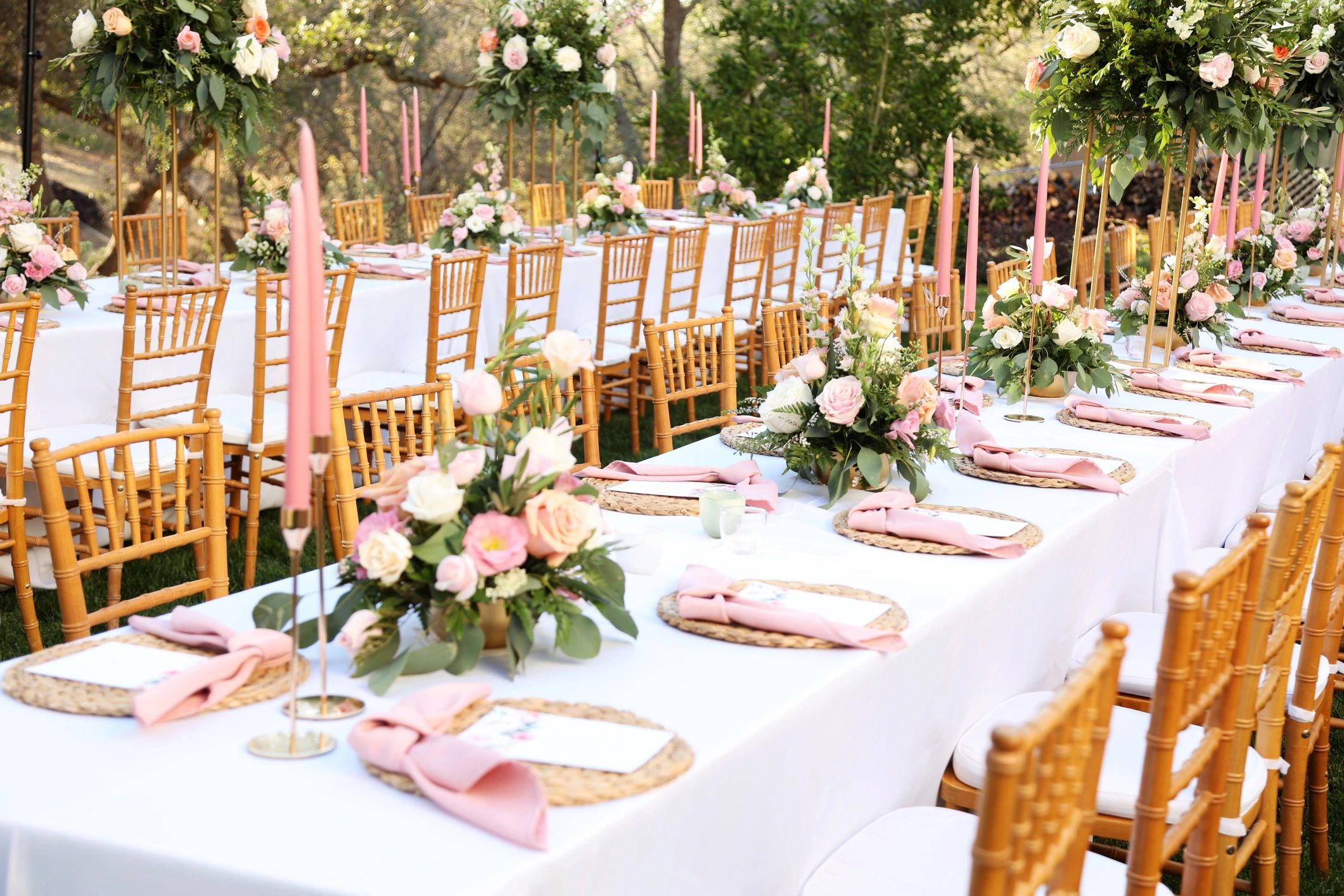 Elegant outdoor dining setup with flowers and pink candles.