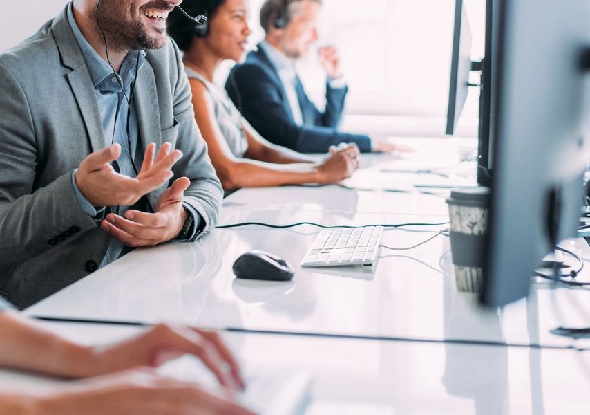Employees working together, wearing headsets and engaging with customers.
