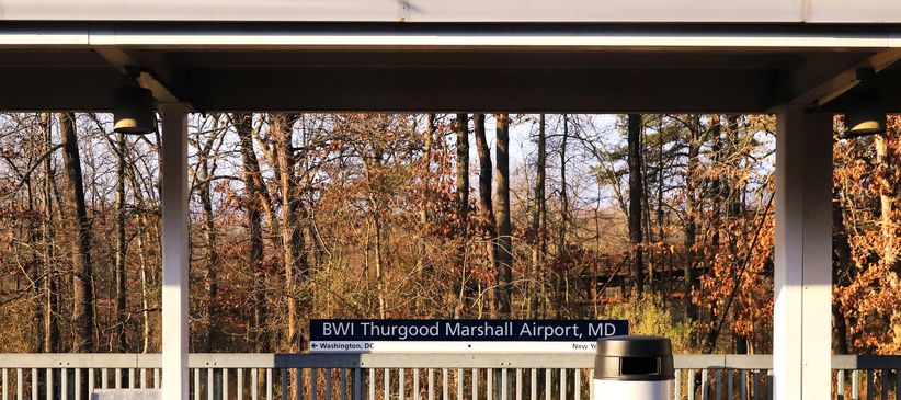 BWI Thurgood Marshall Airport sign at a transit stop with autumn trees.