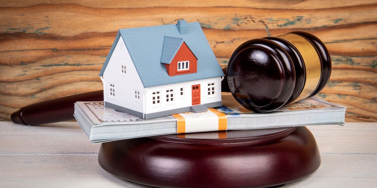 A model house, money stack, and judge's gavel symbolizing real estate law.