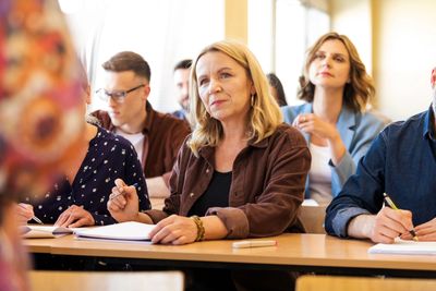Adults attentively participating in a classroom session, taking notes.