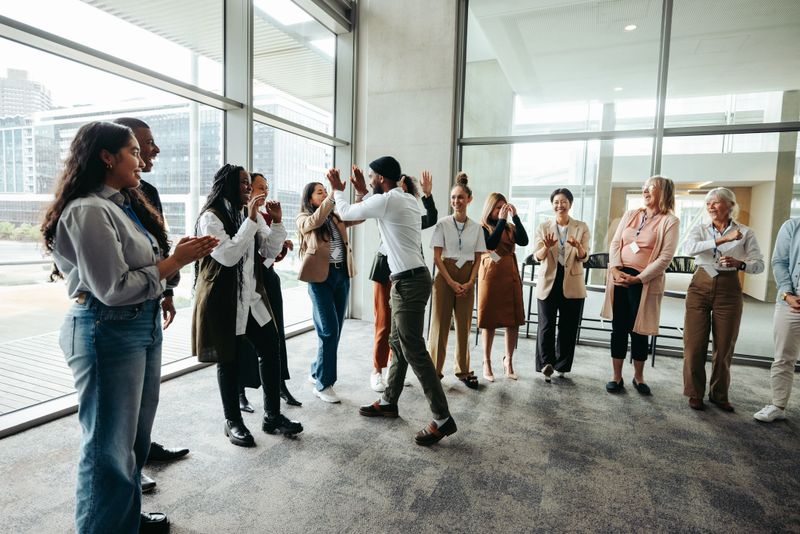 Corporate team celebrating success with high fives during a team building event in a modern office space. Group of colleagues enjoying a successful moment together.