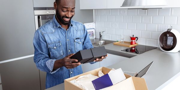 Man happily unboxing a product in his modern kitchen.