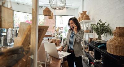 Woman talking on phone in a cozy shop with laptop.