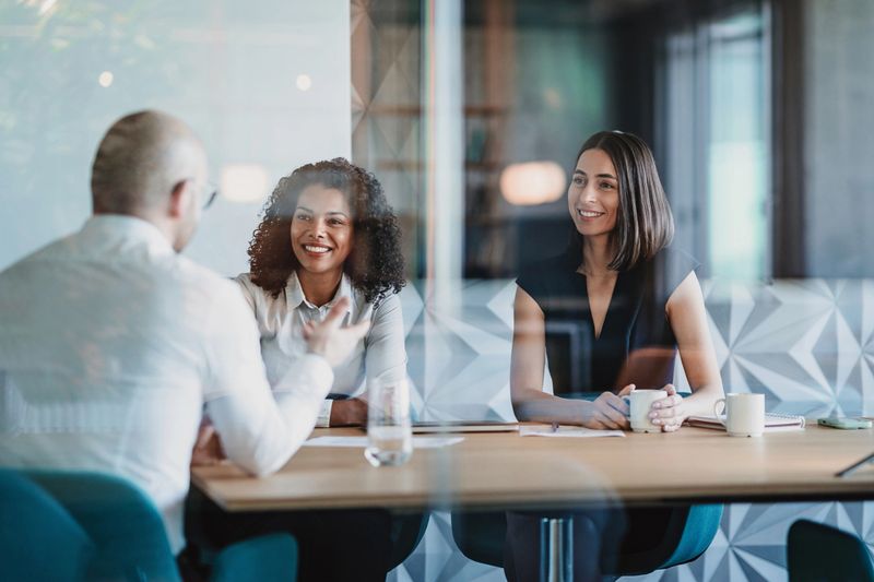 Group of business persons having a meeting behind a glass wall
