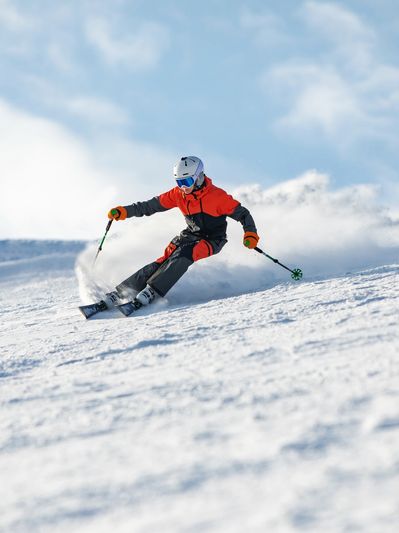 “Skier carving through fresh snow on a bright, clear winter day.”