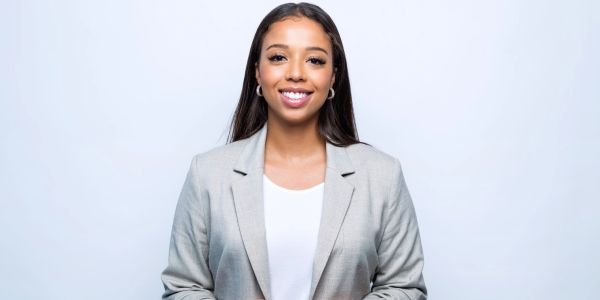 Smiling woman in a light gray blazer against a white background.