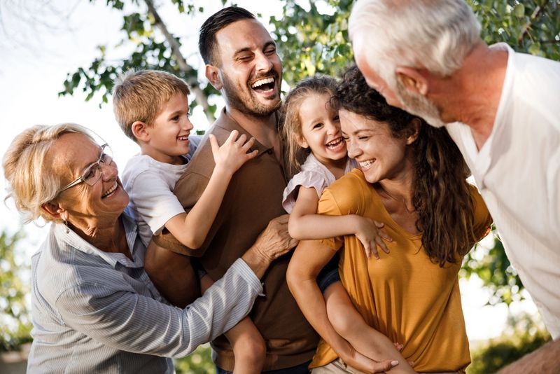 Cheerful multi-generation family having fun in nature. Parents are piggybacking their kids.