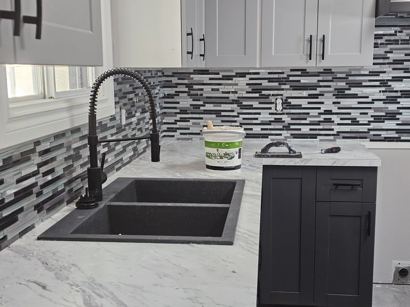 A kitchen renovation, showing the newly installed black and white, modern looking, tiled backsplash.