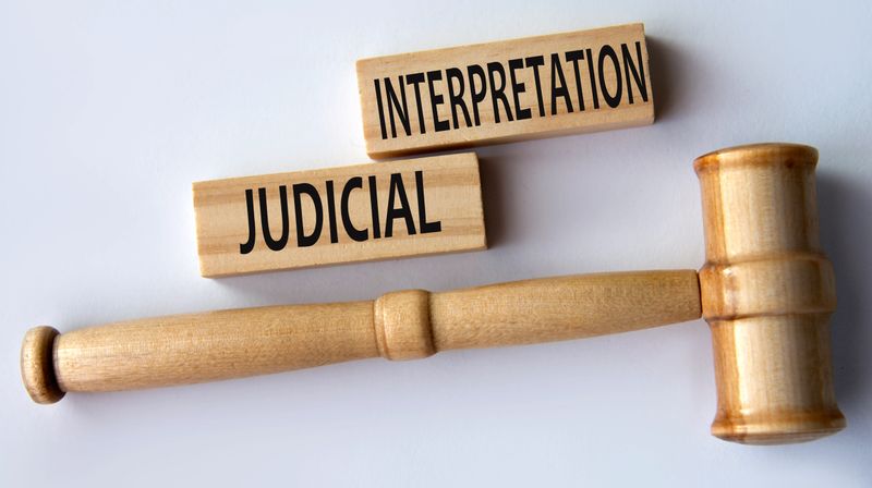 JUDICIAL INTERPRETATION - words on wooden blocks on a white background with a judge's gavel.