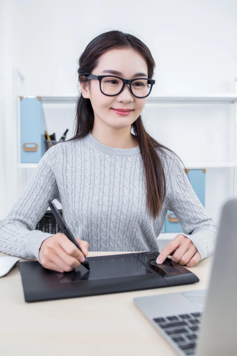 Asian woman graphic designer using graphics tablet and laptop