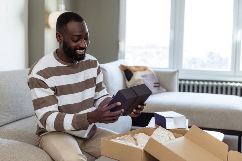 A happy man unboxing a delivery package and experiencing joy in a home setting.