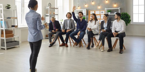 A business meeting with one person raising hand.