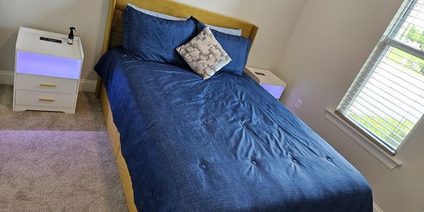 Neatly made bed with blue bedding in a bright bedroom.