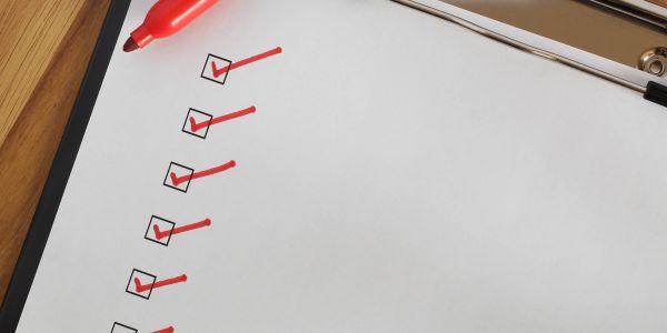 Checklist with red check marks and a red pen.