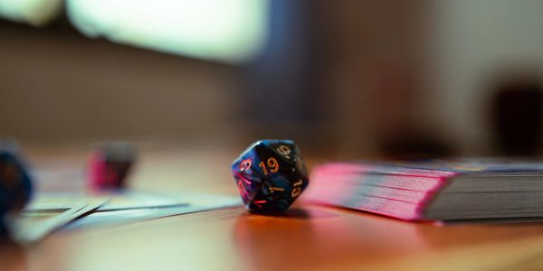 A 20-sided die and a deck of cards on a wooden table.