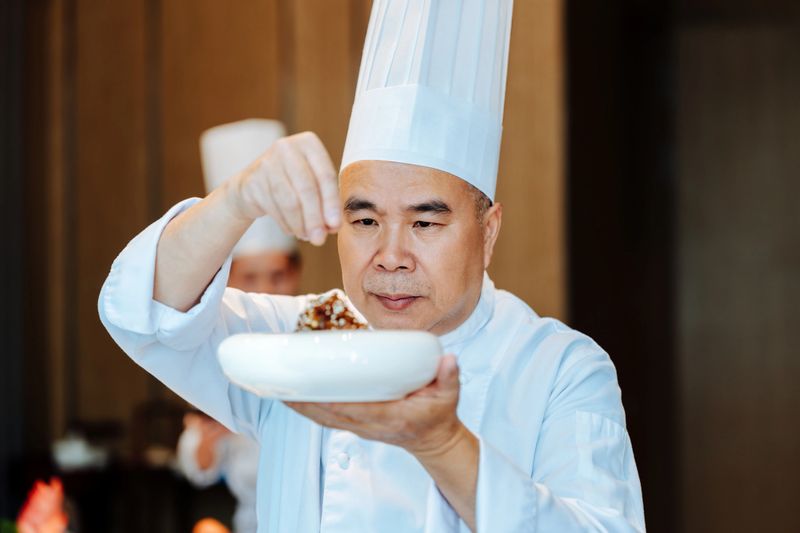 Asian senior chef preparing food.