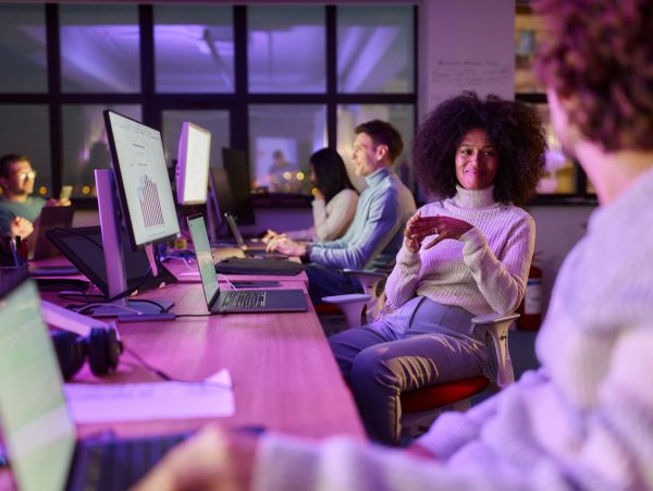 People working late in an office with computer screens glowing.