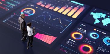 Two people analyzing futuristic data charts on a large digital screen.