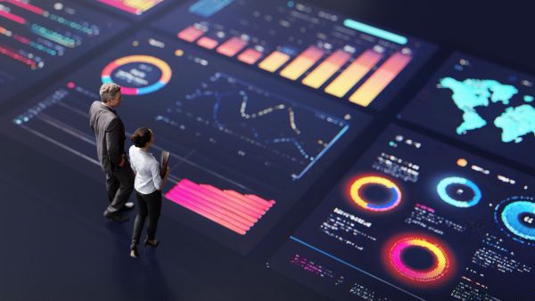 Two people analyzing glowing data visualizations on a digital interface.