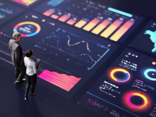 Two professionals analyzing vibrant digital data dashboards with charts and graphs.