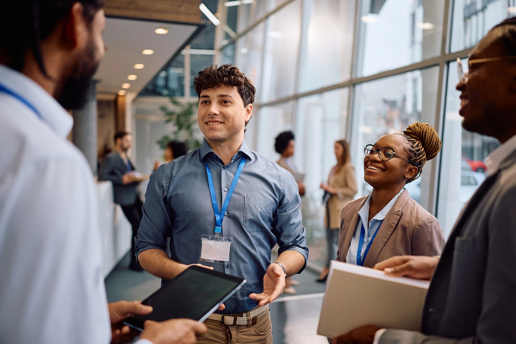 A diverse group of professionals networking and smiling in a modern office setting.