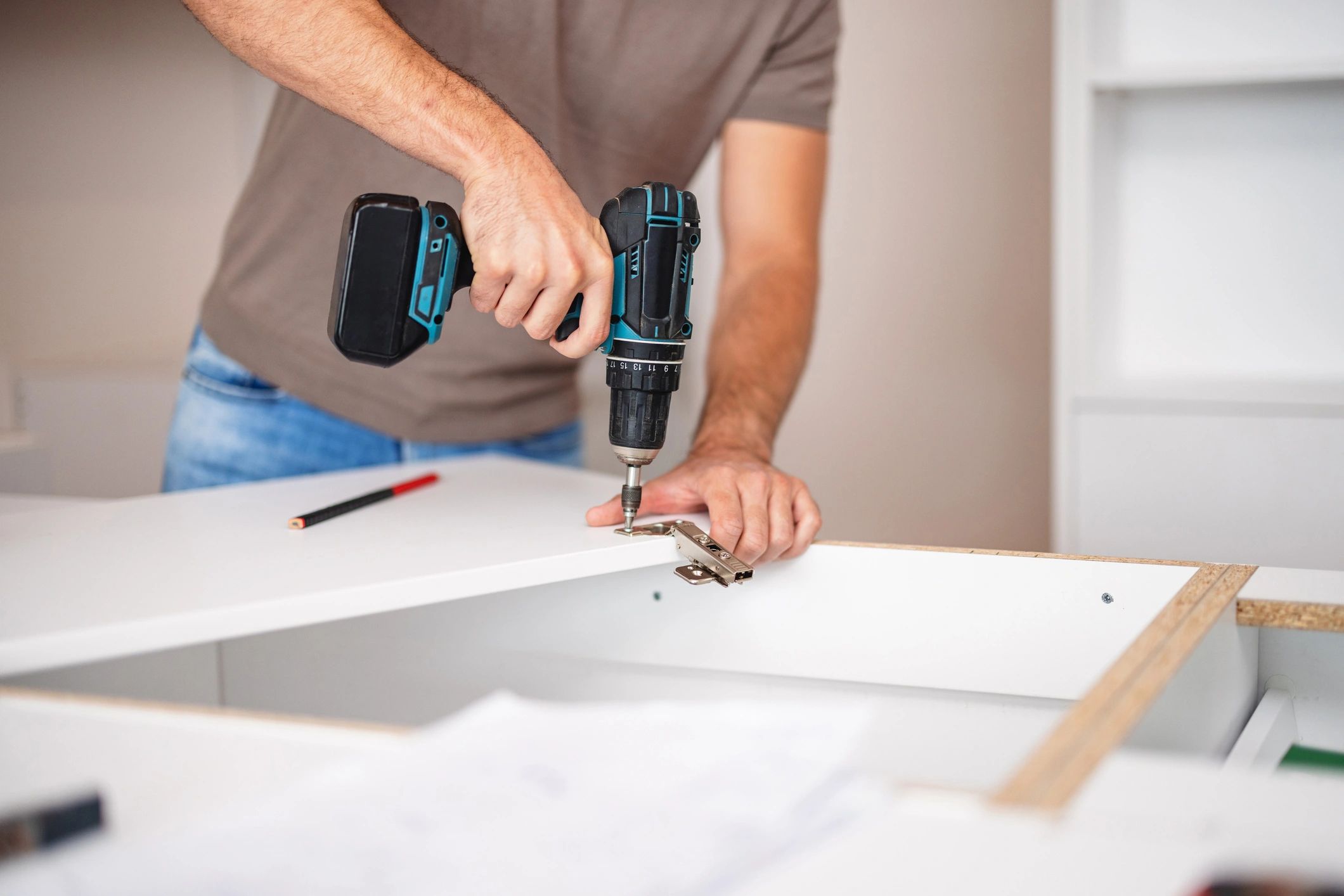 Person assembling furniture with a power drill.