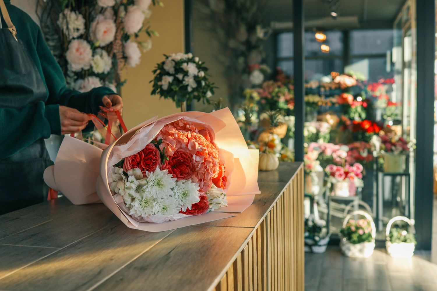 A florist wrapping a vibrant bouquet of red and white flowers in a cozy flower shop.