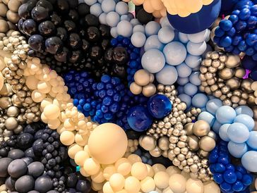 Cluster of balloons in various blue, black, and cream colors.