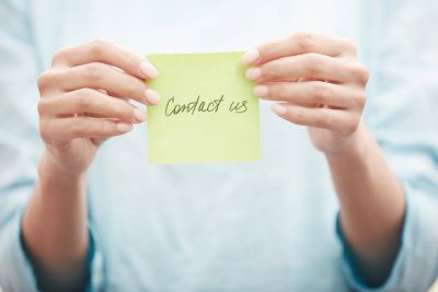 Hands holding a sticky note saying 'Contact us'.