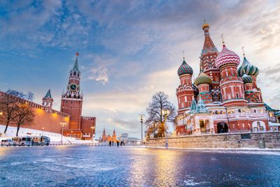 St. Basil's Cathedral and Kremlin tower in Moscow at dusk with colorful sky.