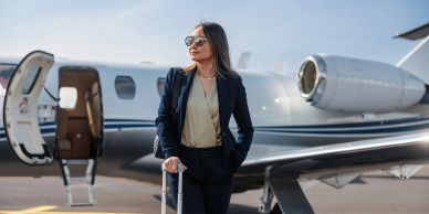 Businesswoman with luggage near a private jet.
