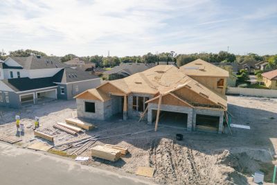 A house under construction in a suburban neighborhood with workers nearby.