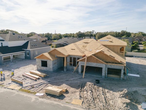 A house under construction with wooden framing and concrete blocks in a residential area.