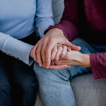 Two people holding hands closely in a comforting gesture.