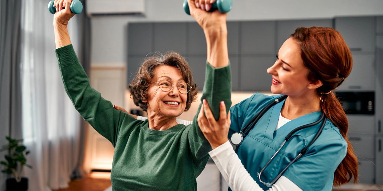 Senior woman exercising with healthcare professional assistance.