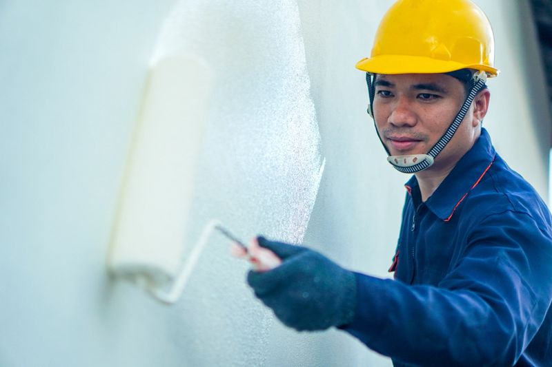 Asian painter is painting white house wall, house decoration and construction idea in village project.
