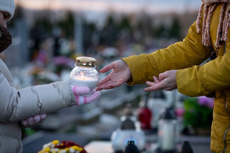 A touching moment sharing a candle in remembrance at a serene cemetery, symbolizing enduring love and loss