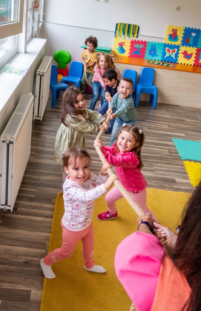 the children are pulling the rope against each other, enjoying themselves and being happy