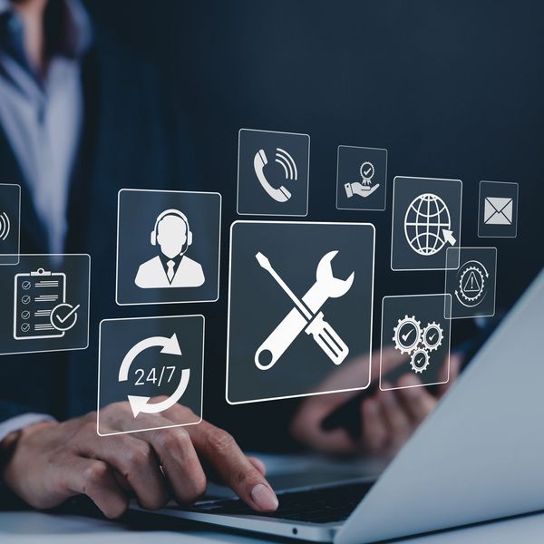 Businessman using laptop with floating service icons.