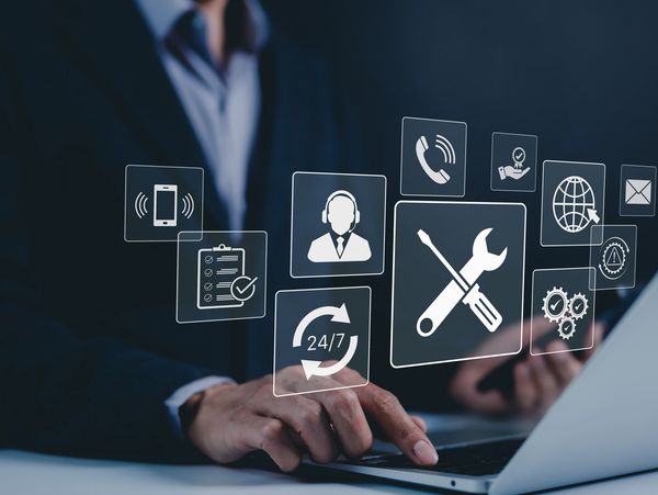 Businessman using laptop with floating service icons.