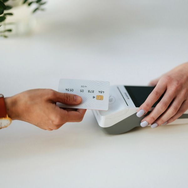 Person making a contactless payment with a credit card and terminal.